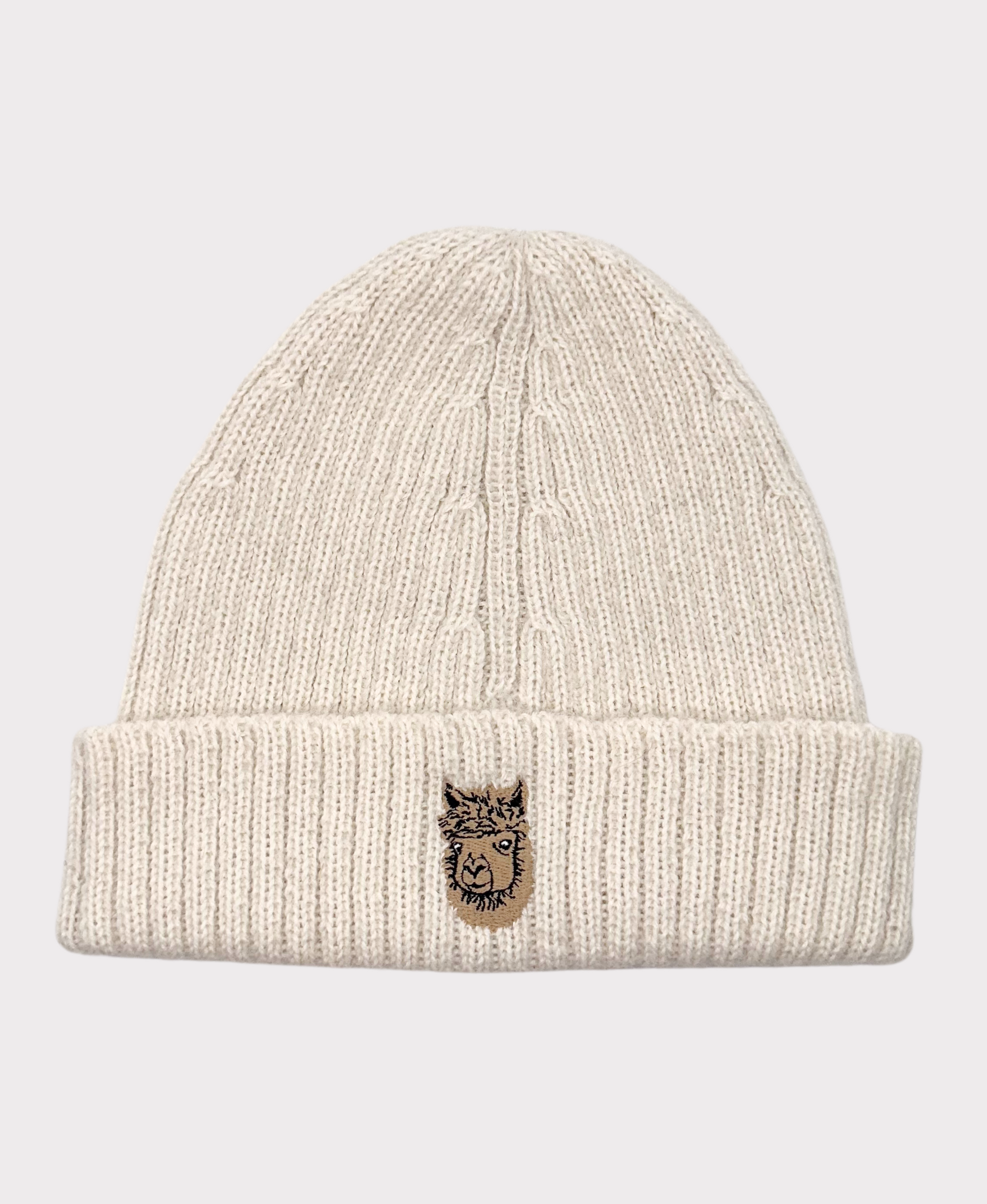 A beige Allen Paca beanie hat made of alpaca wool with a logo on the cuff.