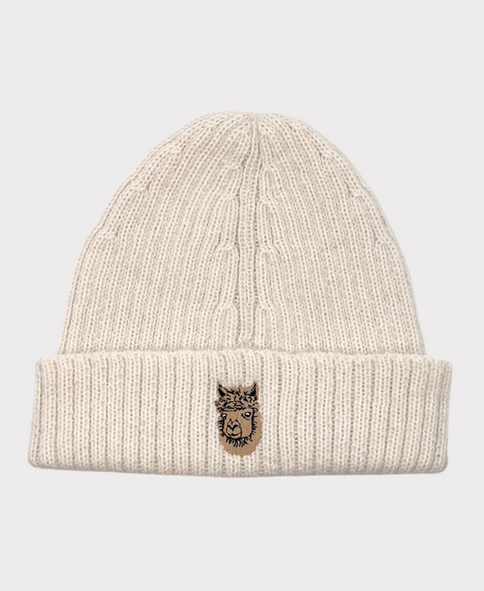 A beige Allen Paca beanie hat made of alpaca wool with a logo on the cuff.